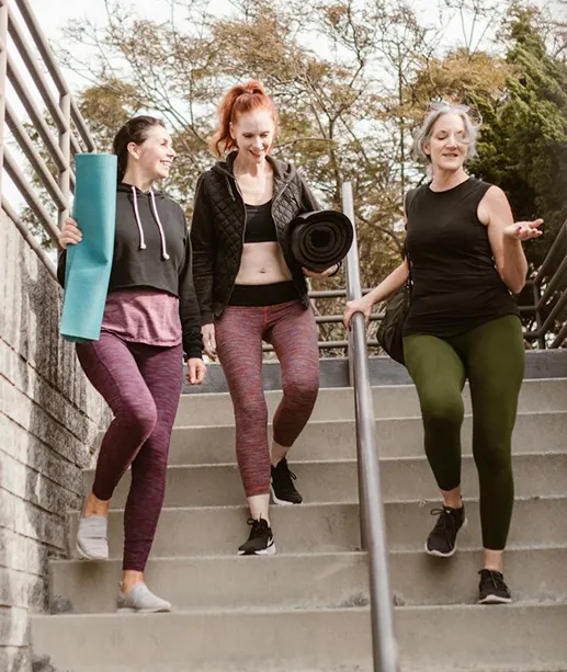 Mujeres vestidas para ir al gimnasio bajando unas escaleras felices